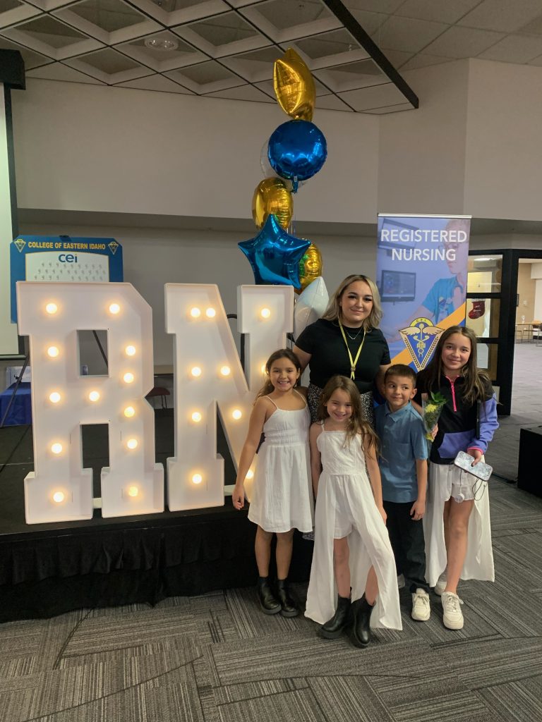 Caitlyn Keelin posing with children in front of RN sign and balloons