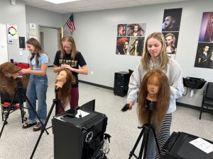 3 women working on cosmetology mannequin heads